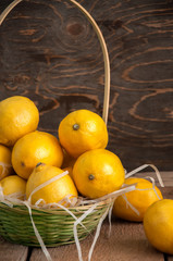 Fresh whole lemons in a basket on a wooden background