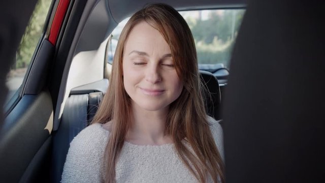 Beautiful woman smiles looking at camera in the backseat of a car.