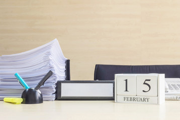 Closeup white wooden calendar with black 15 february word on blurred brown wood desk and wood wall textured background in office room view with copy space in selective focus at the calendar