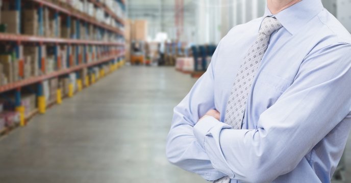 Manager standing with arms crossed in warehouse