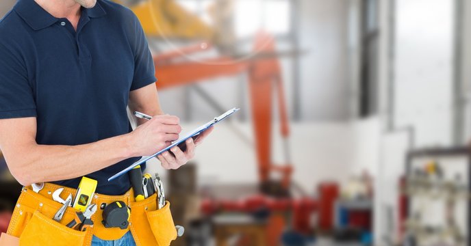 Mid section of handyman with tool belt writing on clipboard - Powered by Adobe