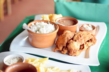 Traditional Brazilian lunch of fried chicken milanesa, rice, beans, and farofa on a plate at restaurant
