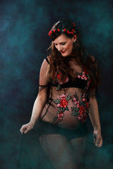 Fototapeta premium Attraktive schwangere Frau in schwarzem Blütenkleid