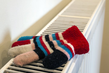 Childs knitted gloves drying on heating radiator after winter da
