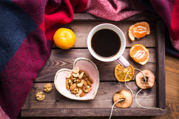 wooden tray with a cup of coffee, nuts and orange on window