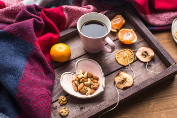 Obraz na płótnie Canvas wooden tray with a cup of coffee, nuts and orange on window