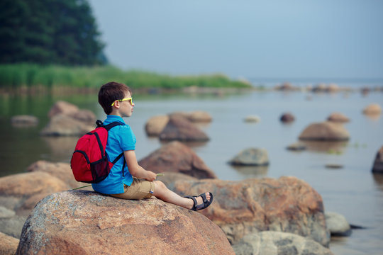 Little boy enjoying scenic view of rocks at the coast of Kasmu, Estonia