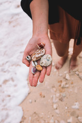 Sea shells and stones in the hand on the beach of Indian ocean, Indonesia, Bali