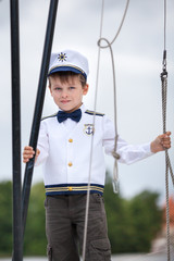 Cute toddler boy in captain costume enjoying boat ride