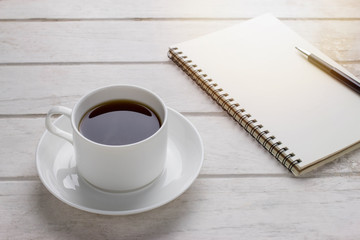 Obraz na płótnie Canvas Coffee cup & Notebook on white wooden table