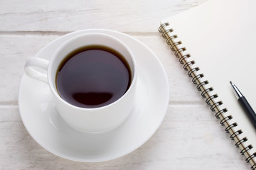 Coffee cup & Notebook on white wooden table