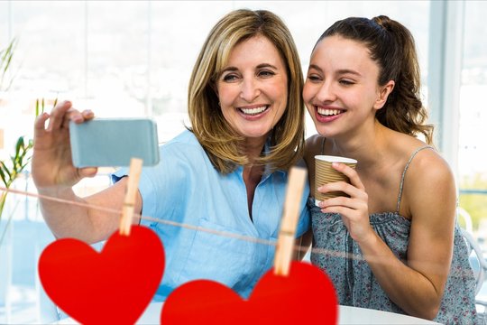 Women taking a selfie on mobile phone against red hanging hearts
