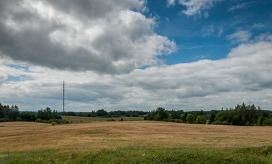 summer rural hilly landscape. the agricultural field under the cloudy sky
