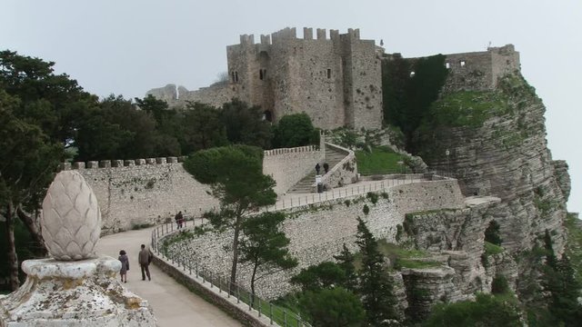 Venere Castle in Erice Sicily, with low clouds. Tourist are walking towards the castle