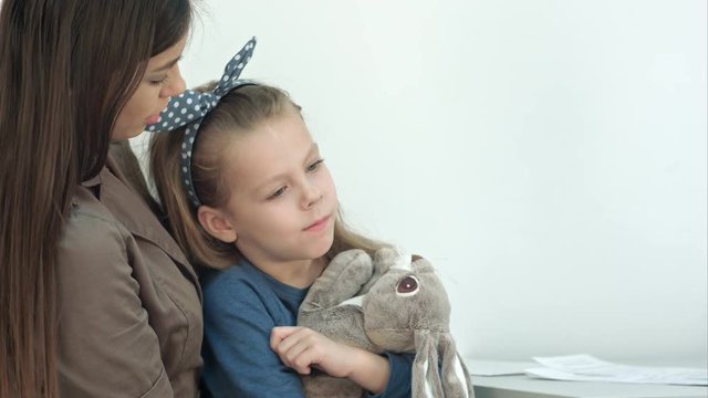Young mother and her little daughter with bunny at the doctor