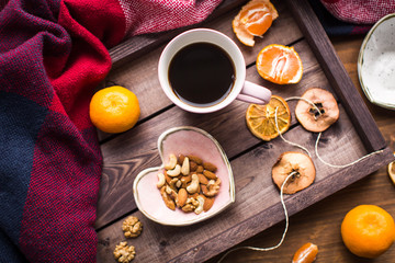 wooden tray with cup of coffee, nuts and orange