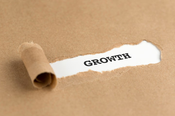 The text GROWTH appearing behind torn brown paper