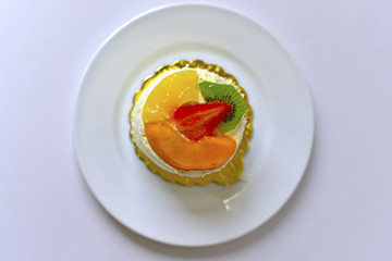 Delicious fruit cake with strawberry, peach, kiwi and pineapple covered with cream