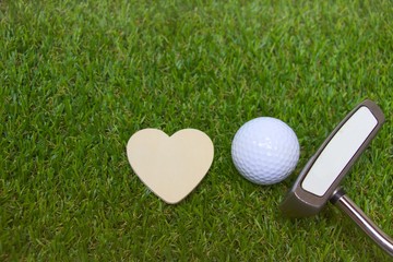 golf ball and wooden heart on green grass