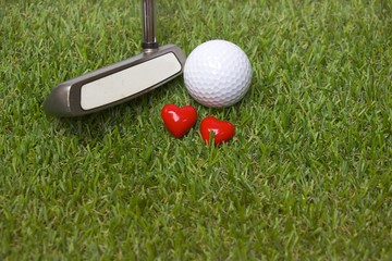 Golf ball and putter are on the green course with love sign