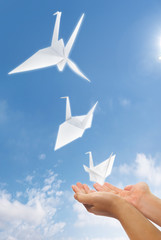 hand let go origami paper pigeon into the sky