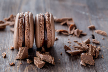 Chocolate macarons on a rustic wooden table. 