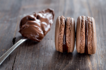 Chocolate macarons on a rustic wooden table. 