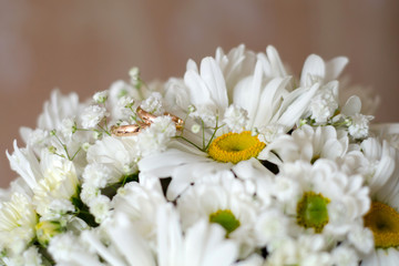 Wedding rings on a bouquet of daisies