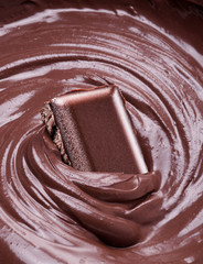Melted chocolate and piece of chocolate bar dipped in it.