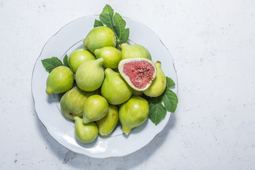 Plate full of ripe fig fruits on the old kitchen table.