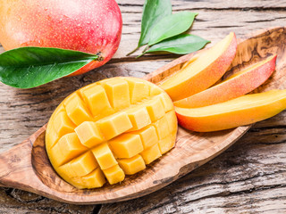 Mango fruit and mango cubes on the wooden table.