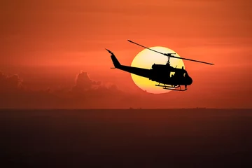 Wall murals Helicopter Flying helicopter silhouettes on sunset background.   The patrol helicopter flying in the twilight sky. 