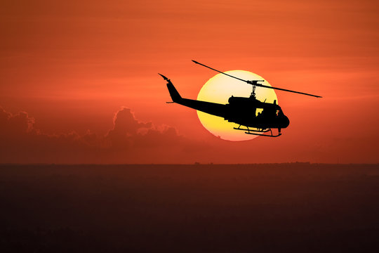 Flying helicopter silhouettes on sunset background.
 The patrol helicopter flying in the twilight sky. 