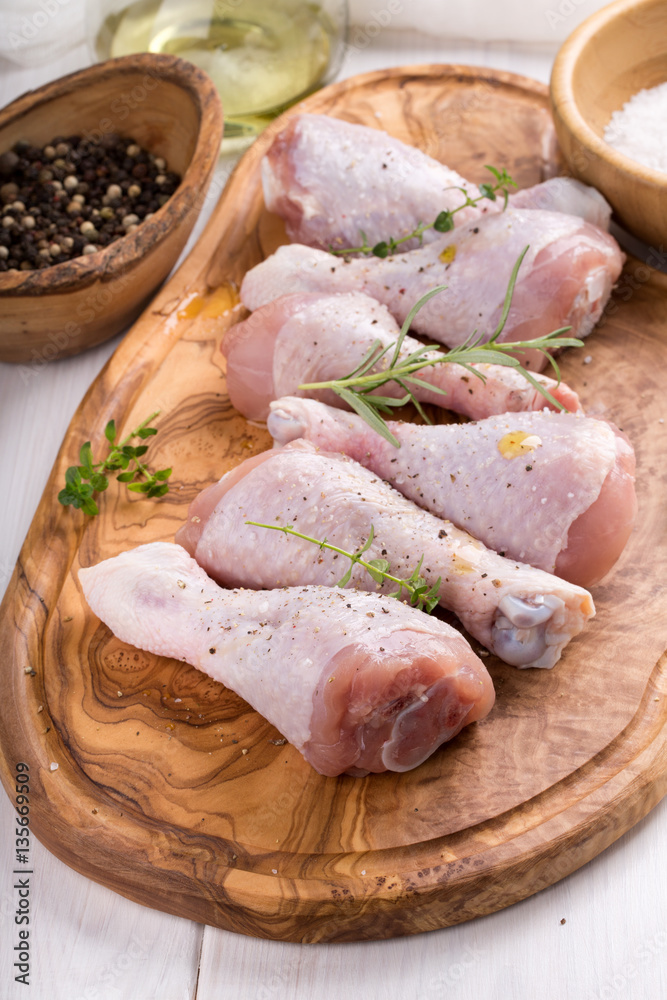 Wall mural raw chicken drumsticks on cutting board. uncooked chicken legs.