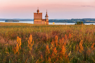 Wooden church on the top of the hill. Vershinino village sunset view. Arkhangelsk region, Northern Russia.