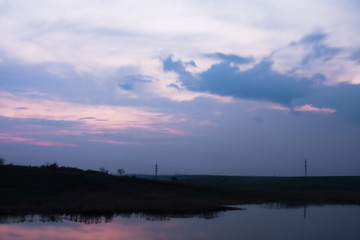 Field, river and beautiful sky and clouds reflected