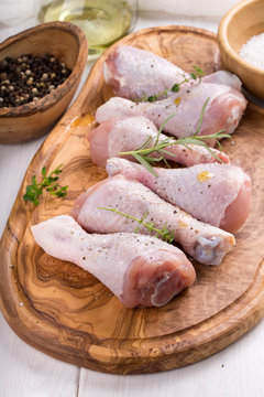Raw chicken drumsticks on cutting board. Uncooked chicken legs.