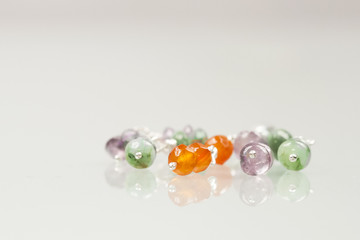 Silver jewels with colorful precious stones and light grey background
