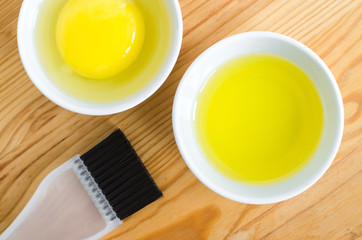 Olive oil and raw egg in a small ceramic bowls for preparing homemade spa face and hair masks. Ingredients for diy cosmetics.