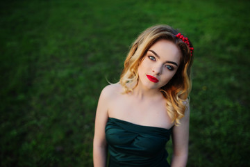 Naklejka premium Yong elegance blonde girl at green dress on the garden in spring