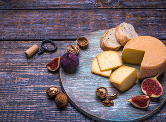 Cork, bottle screw and a set of products - cheese, grapes, nuts, olives, figs on a wooden board, background
