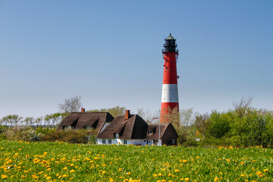 Leuchtturm mit Reetdach gedeckten H&auml;usern an der Nordsee