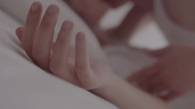 Romantic young couple enjoying sensual foreplay in bed. Focus on hands man and woman.
