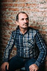 Obraz premium Handsome middle aged man is dressed in a casual clothing. Red brick wall background.