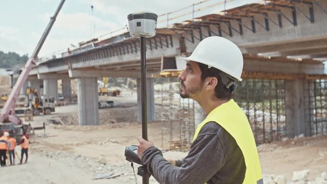 Construction supervisor inspecting a large road construction site using GPS equipment