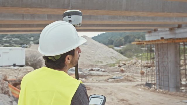 Construction supervisor inspecting a large road construction site using GPS equipment