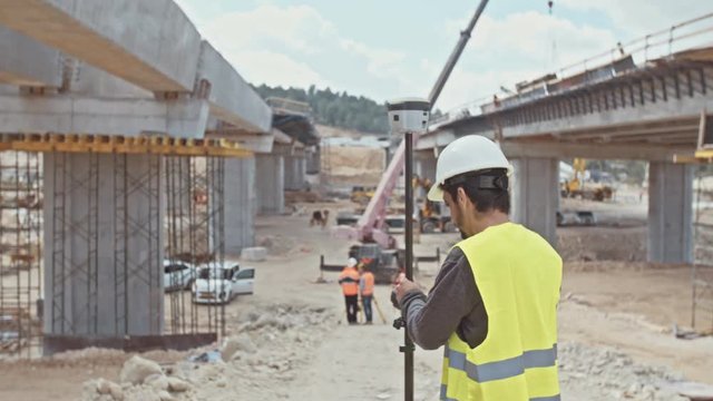 Construction supervisor inspecting a large road construction site using GPS equipment