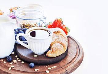 Healthy and colorful breakfast - cup of coffee with homemade granola, waffles, muffins,almond,hazelnuts,various fresh fruits, berries and milk on old wooden table.