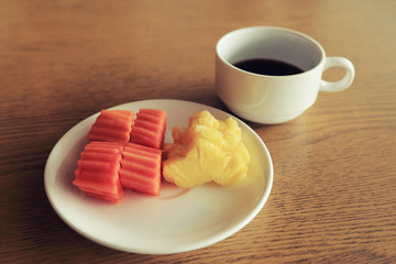 Diet set, plate of fresh fruits with a cup of black coffee on wo