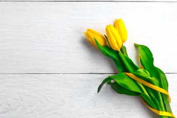 flowers yellow tulips on a white wooden board background